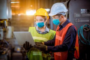 Worker and engineer under inspection and checking production process on factory station by wearing safety mask to protect for pollution and virus in factory